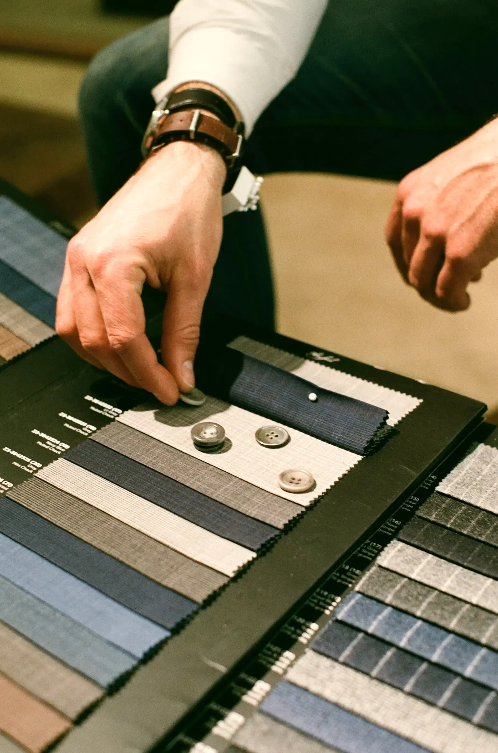 A person holding fabric swatches against a wall to compare colours